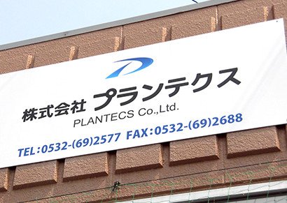 白い外壁と駐車スペースを備えた事業所外観を道路側から見た写真